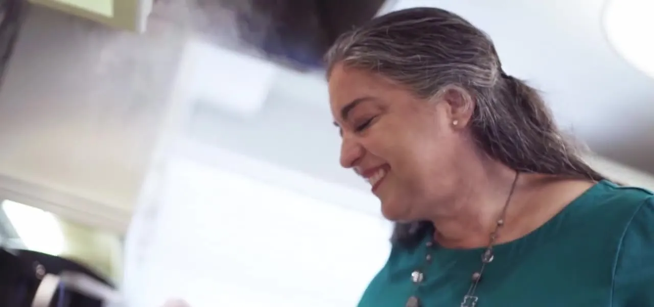 A woman cooking at home, smiling as she stirs a pot